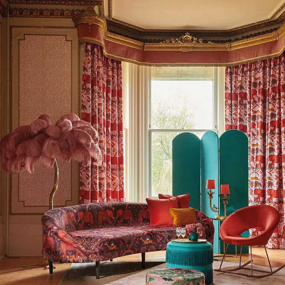 red patterned curtains and a green modesty screen in a maximalist room.